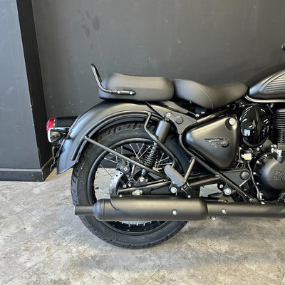 Black motorcycle parked against a dark wall on a concrete surface