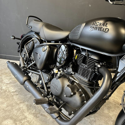 Black Royal Enfield motorcycle on a concrete floor with a gray wall background