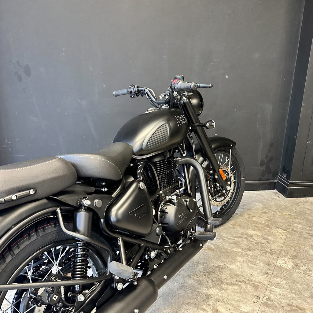 Black motorcycle parked against a gray wall