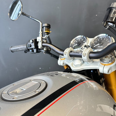 Close-up of a motorcycle's handlebar, mirrors, and dashboard against a dark background.