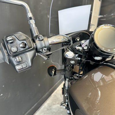 Close-up of a motorcycle handlebar with controls and mirror.