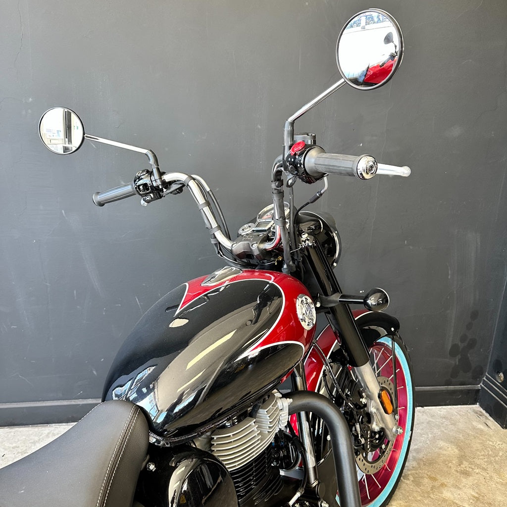 Red and black motorcycle with chrome details against a gray wall.