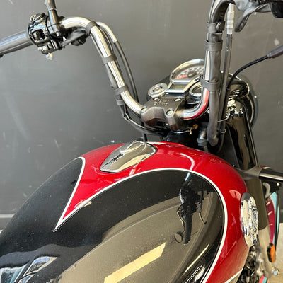 Close-up of a motorcycle's handlebar and red fuel tank against a blurred background