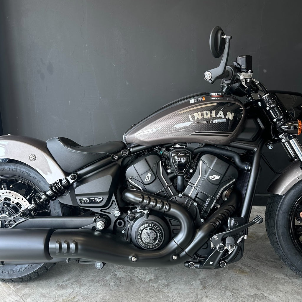 A side profile view of an Indian Cobra motorcycle with a dark metallic gray and black finish, featuring the 'INDIAN' logo on the fuel tank.
