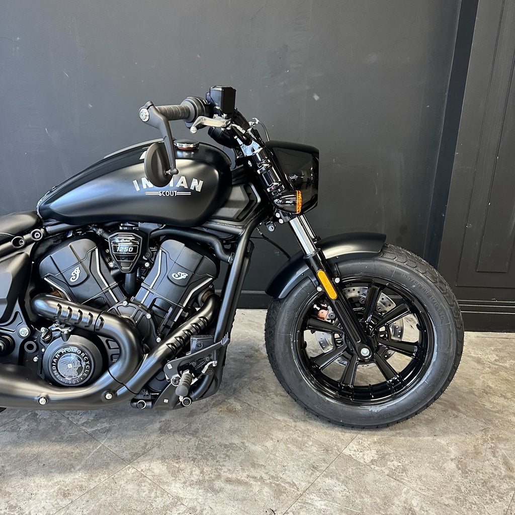 A black Indian Motorcycle Hoss cruiser bike photographed indoors against a dark gray paneled wall and gray stone floor.