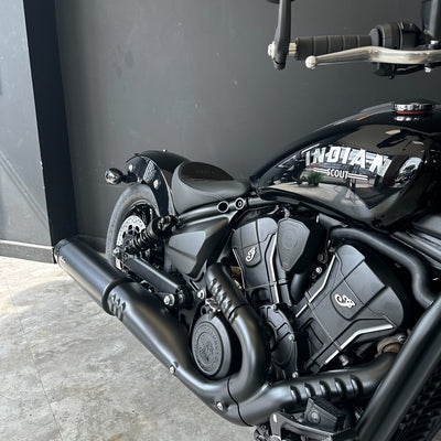 Close-up of a black cruiser motorcycle with a matte black finish, featuring a custom 'TWENTYTWO' decal on the side panel, set against a dark gray wall.