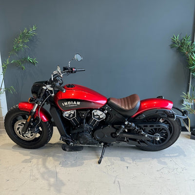 Red Indian motorcycle parked indoors with a gray wall and plants in the background
