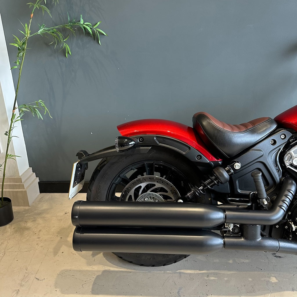 Red and black motorcycle parked indoors with a plant in the background