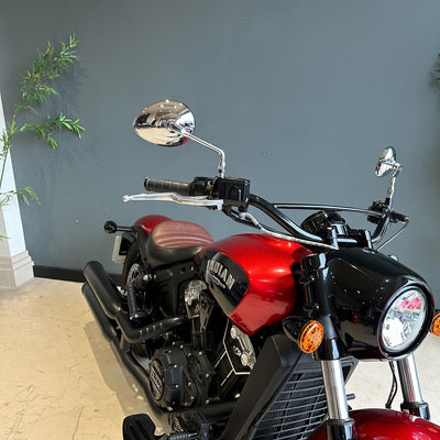 Red motorcycle with chrome mirrors against a gray wall