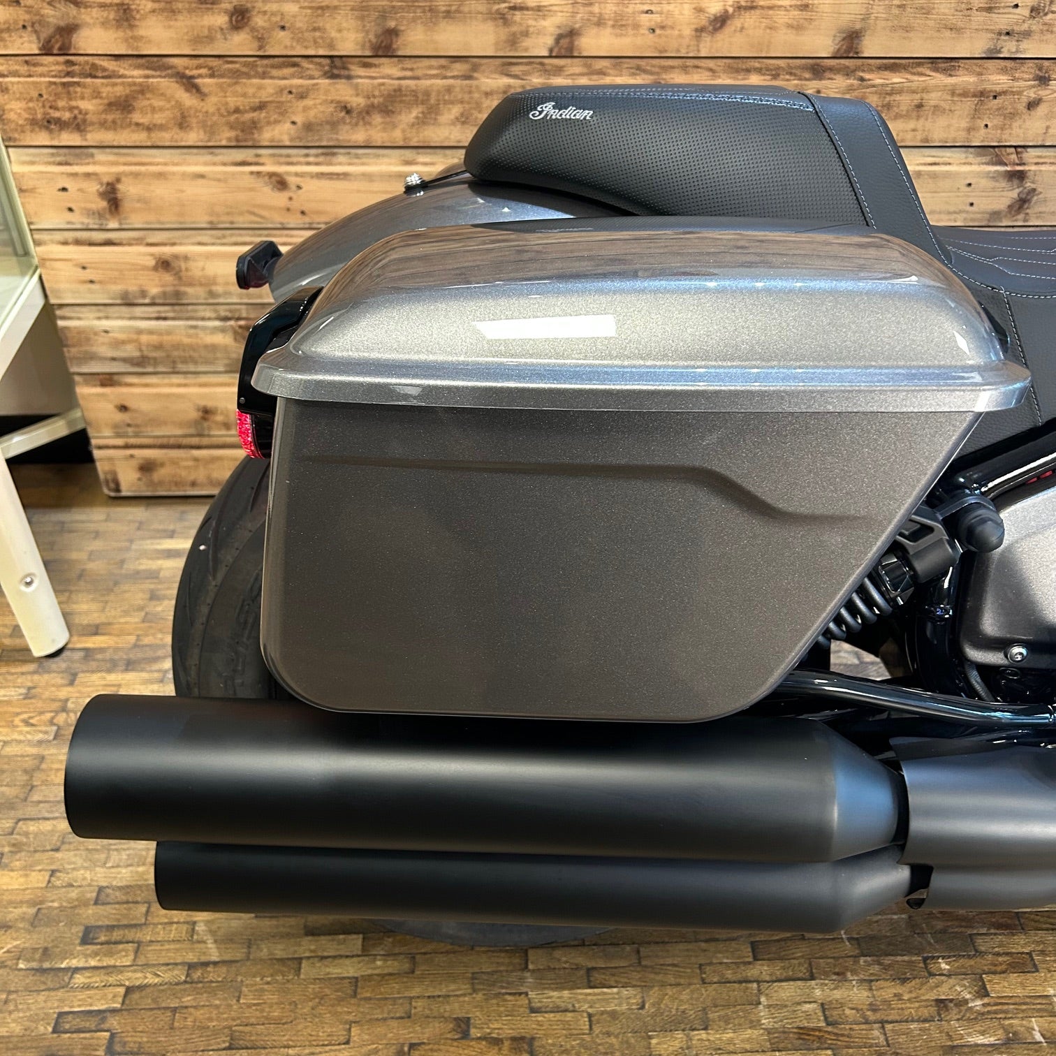 Motorcycle with a large storage compartment against a wooden wall.