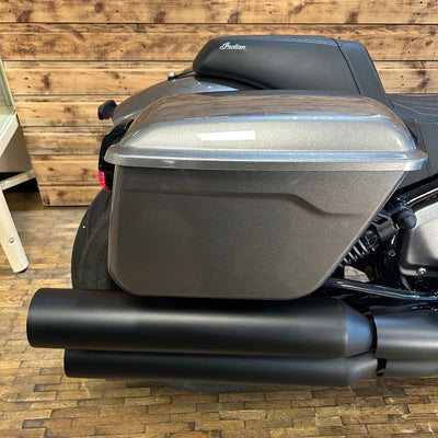 Motorcycle with a large storage compartment against a wooden wall.