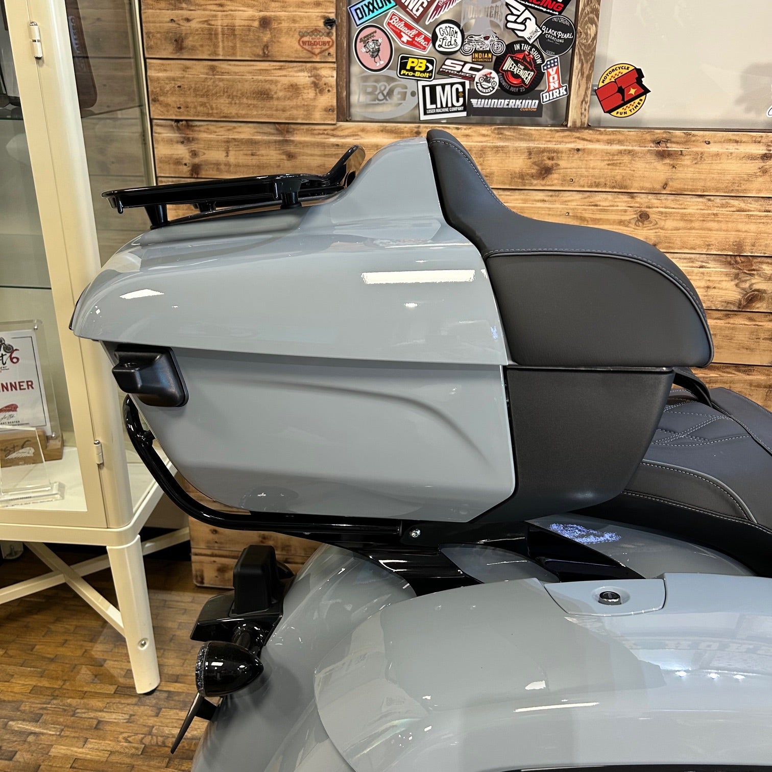 Gray motorcycle with a wooden wall and stickers in the background