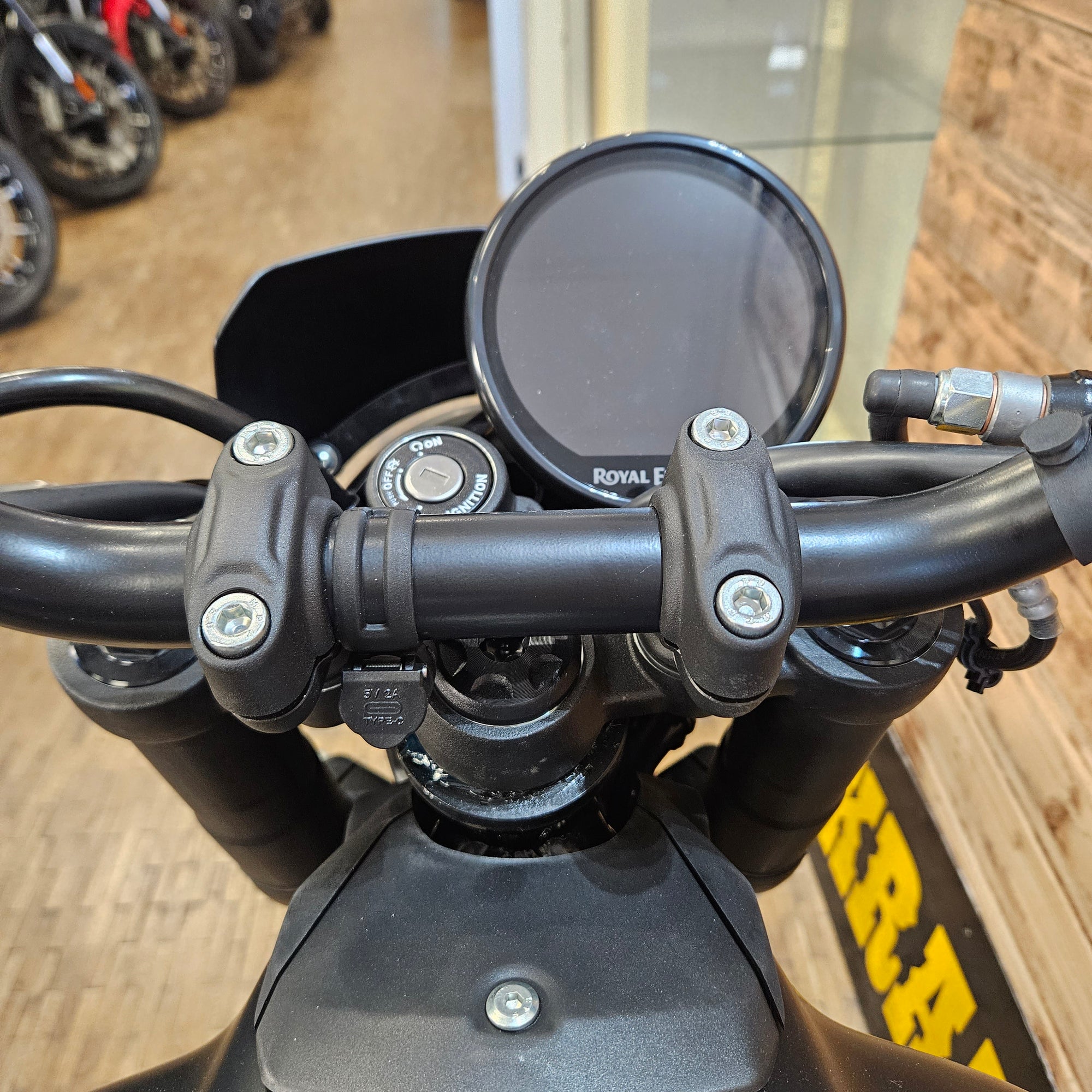Close-up of a motorcycle handlebar with mirrors and visible brand logo.