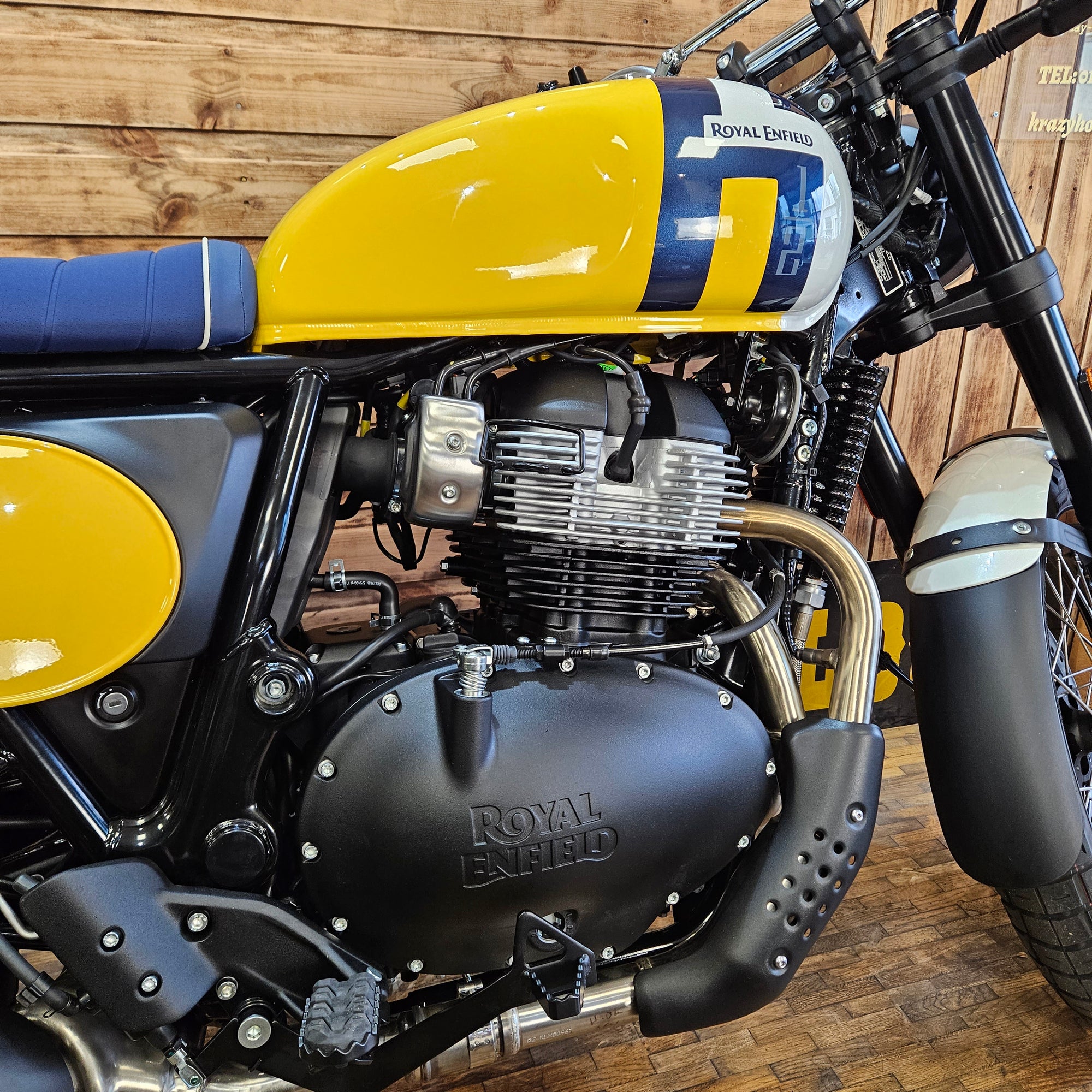 Close-up of a Royal Enfield motorcycle engine on a wooden floor.