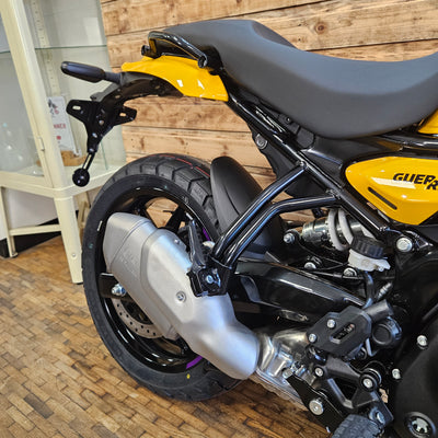 Close-up of a motorcycle's front wheel and suspension on a wooden floor.
