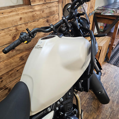 Close-up of a motorcycle seat and handlebars on a wooden floor.