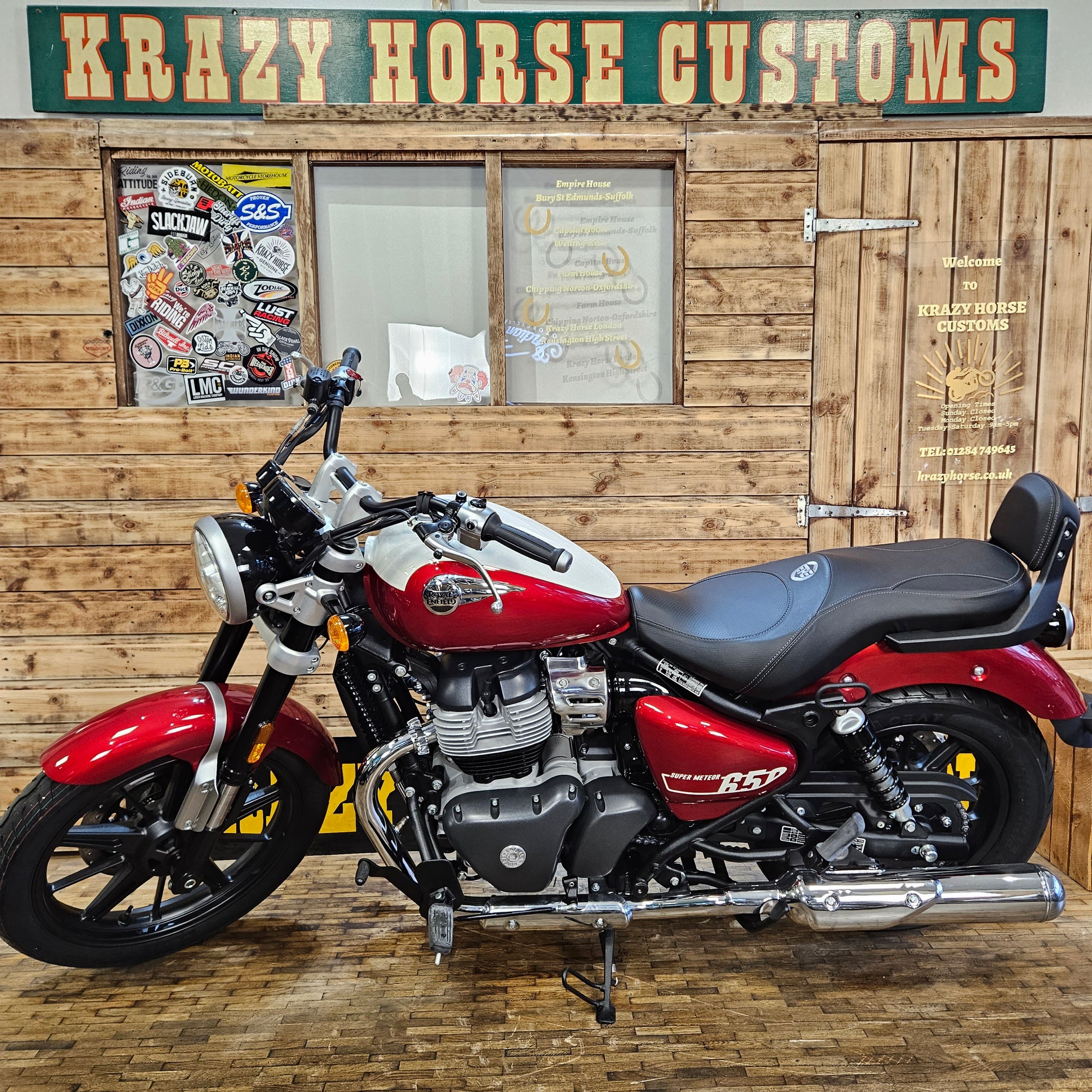 Red motorcycle parked inside a building with wooden walls and a sign.