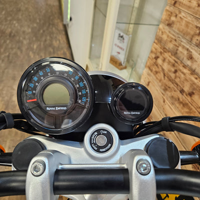 Close-up of motorcycle dashboard with speedometer and tachometer on a wooden background