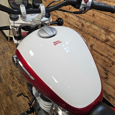 Close-up of a motorcycle's white and red fuel tank on a wooden floor.