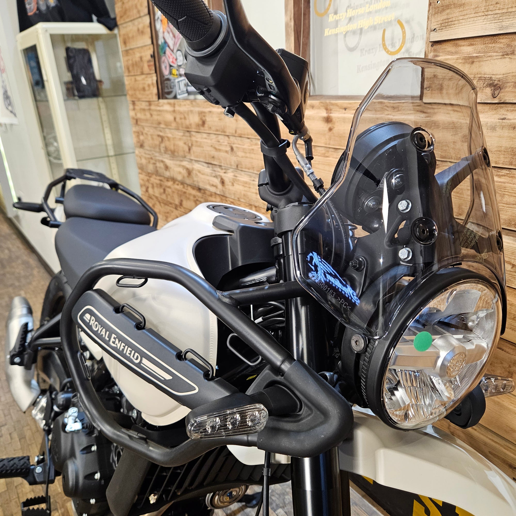 Close-up of a motorcycle's headlight and handlebar with a wooden wall background
