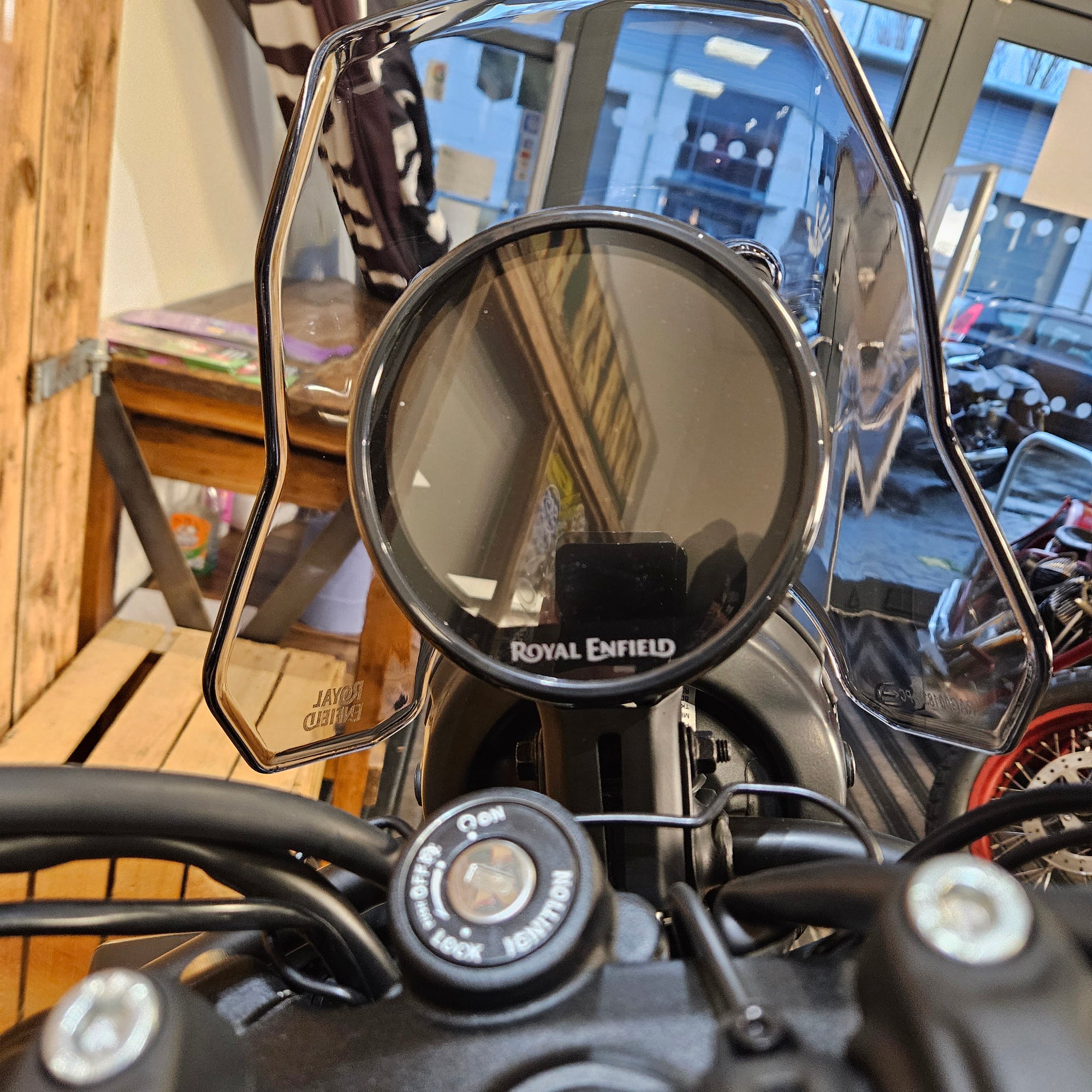 Close-up of a motorcycle mirror with a blurred indoor background