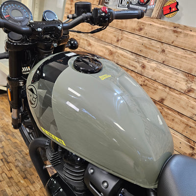 Close-up of a motorcycle's fuel tank and handlebar against a wooden background