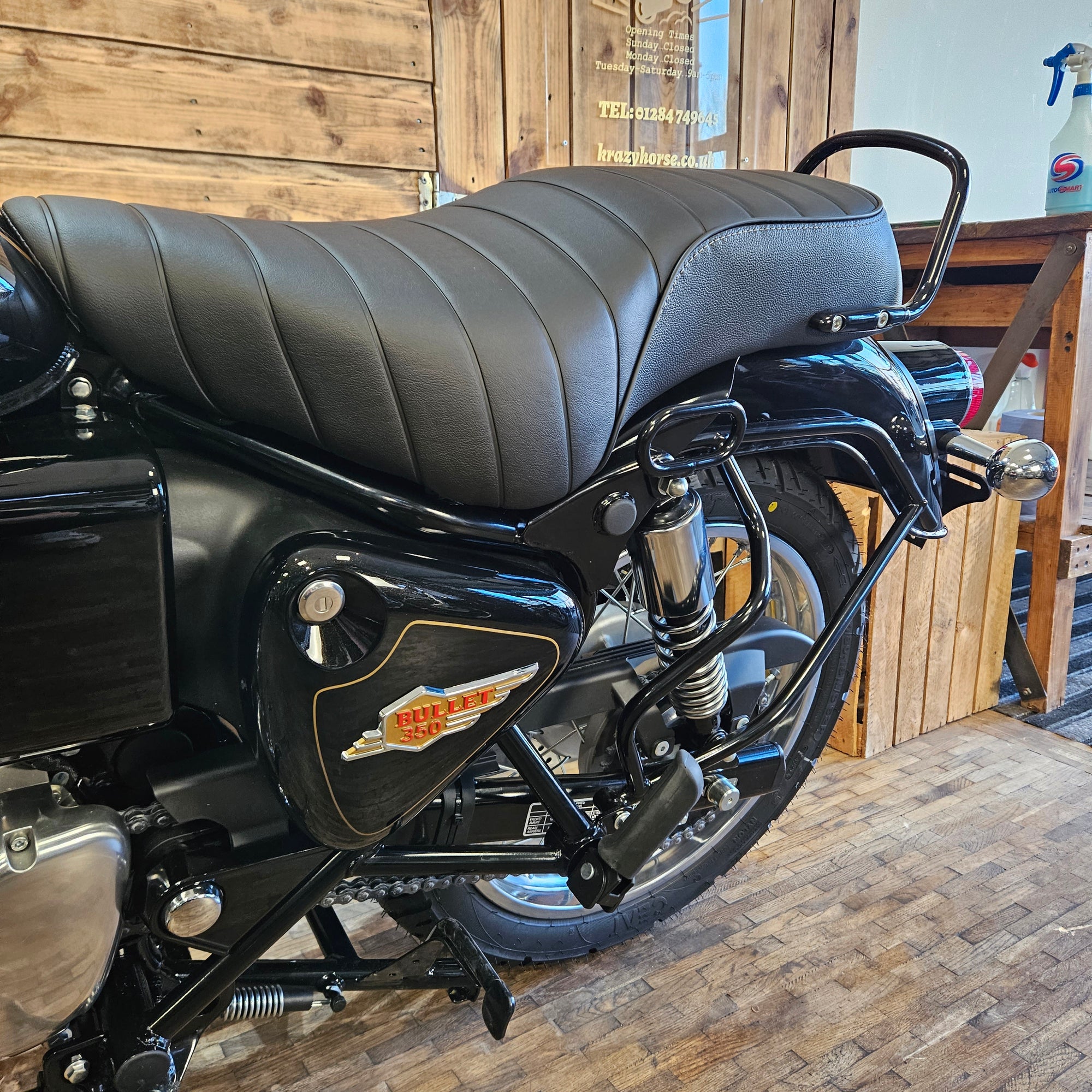 Close-up of a motorcycle seat and front wheel on a wooden platform