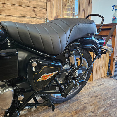Close-up of a motorcycle seat and front wheel on a wooden platform