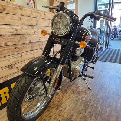 Motorcycle on display in a showroom with wooden floor and brick wall.