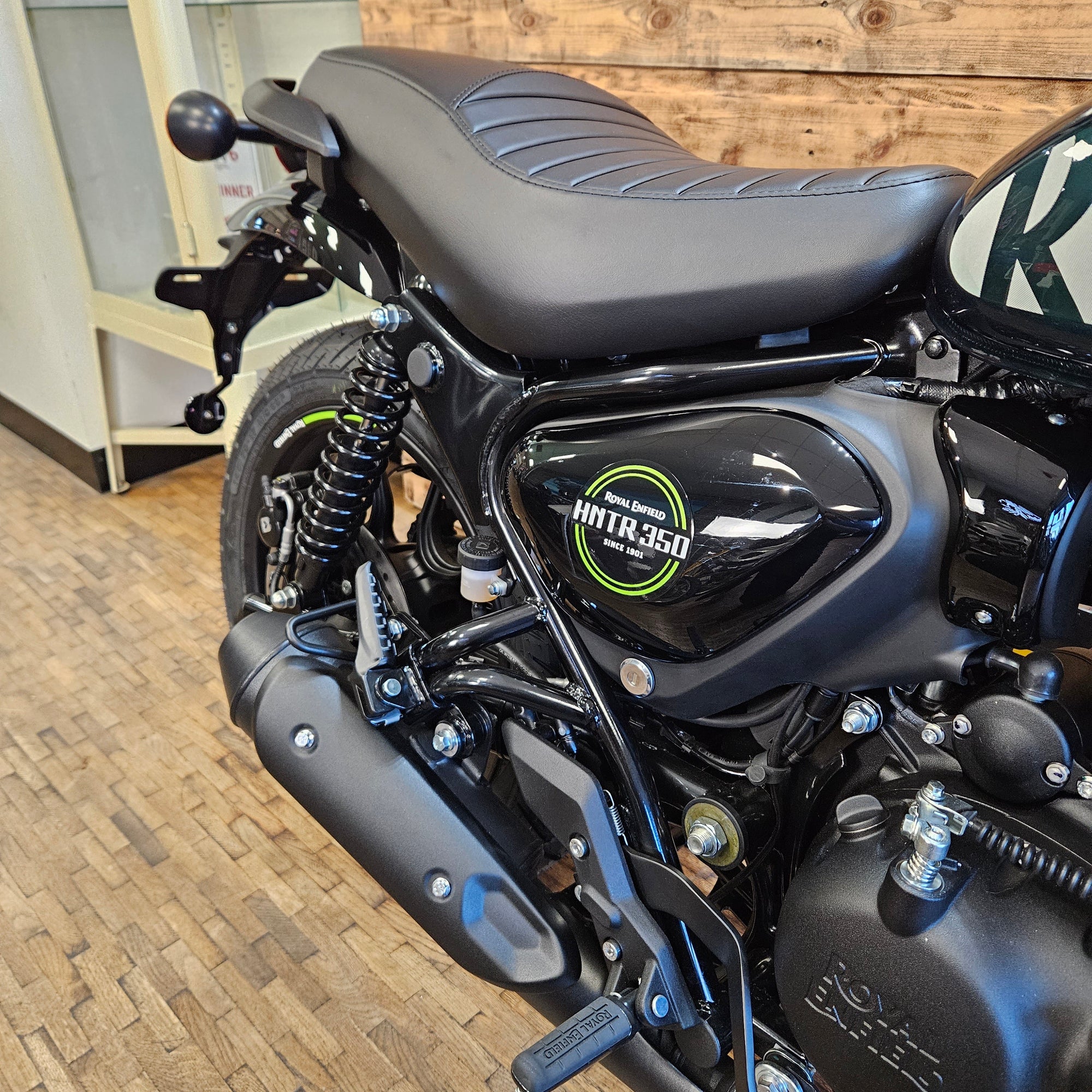 Close-up of a motorcycle with a visible brand logo on a wooden floor.