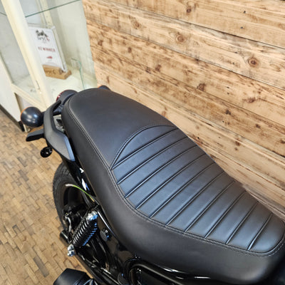 Close-up of a motorcycle seat with a wooden floor background