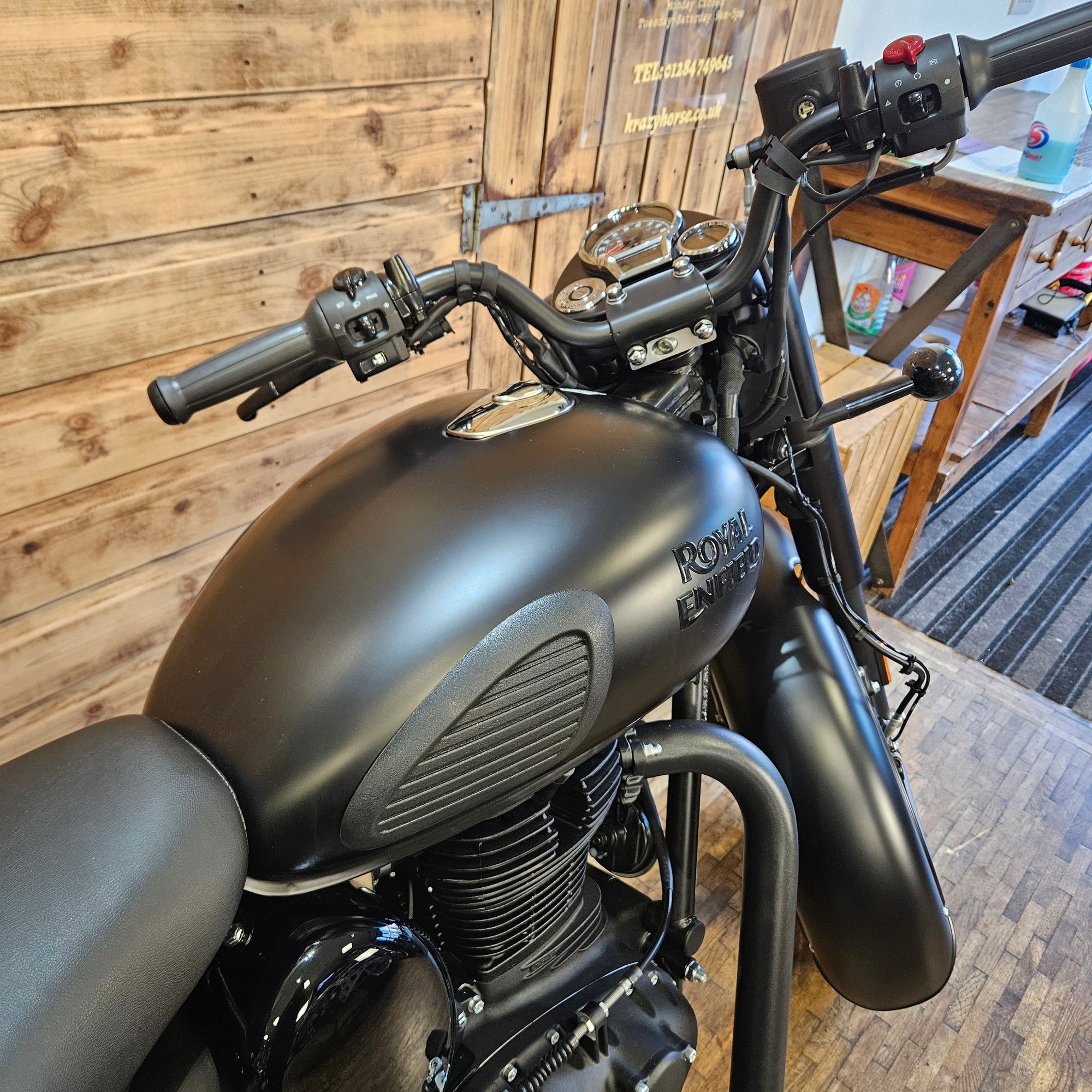 Black motorcycle on a wooden floor with a blurred background
