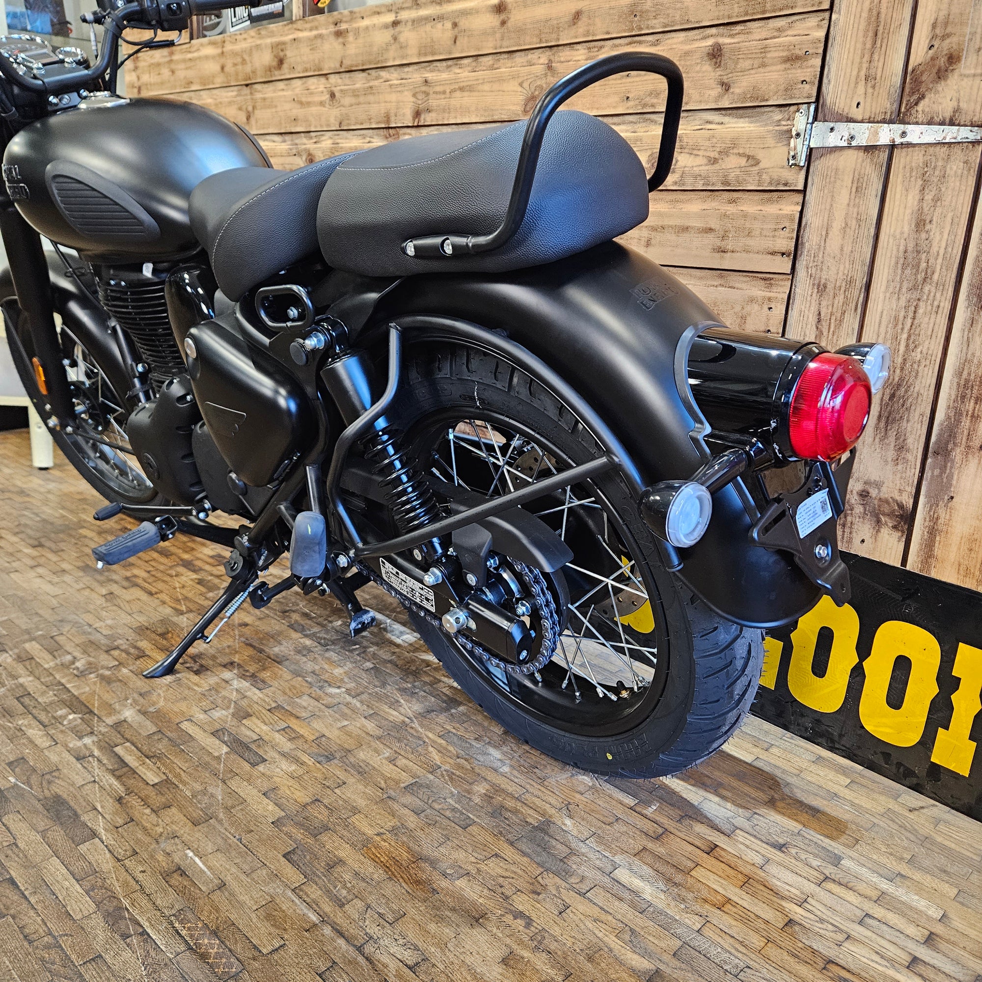 Black motorcycle with a red light on a wooden floor