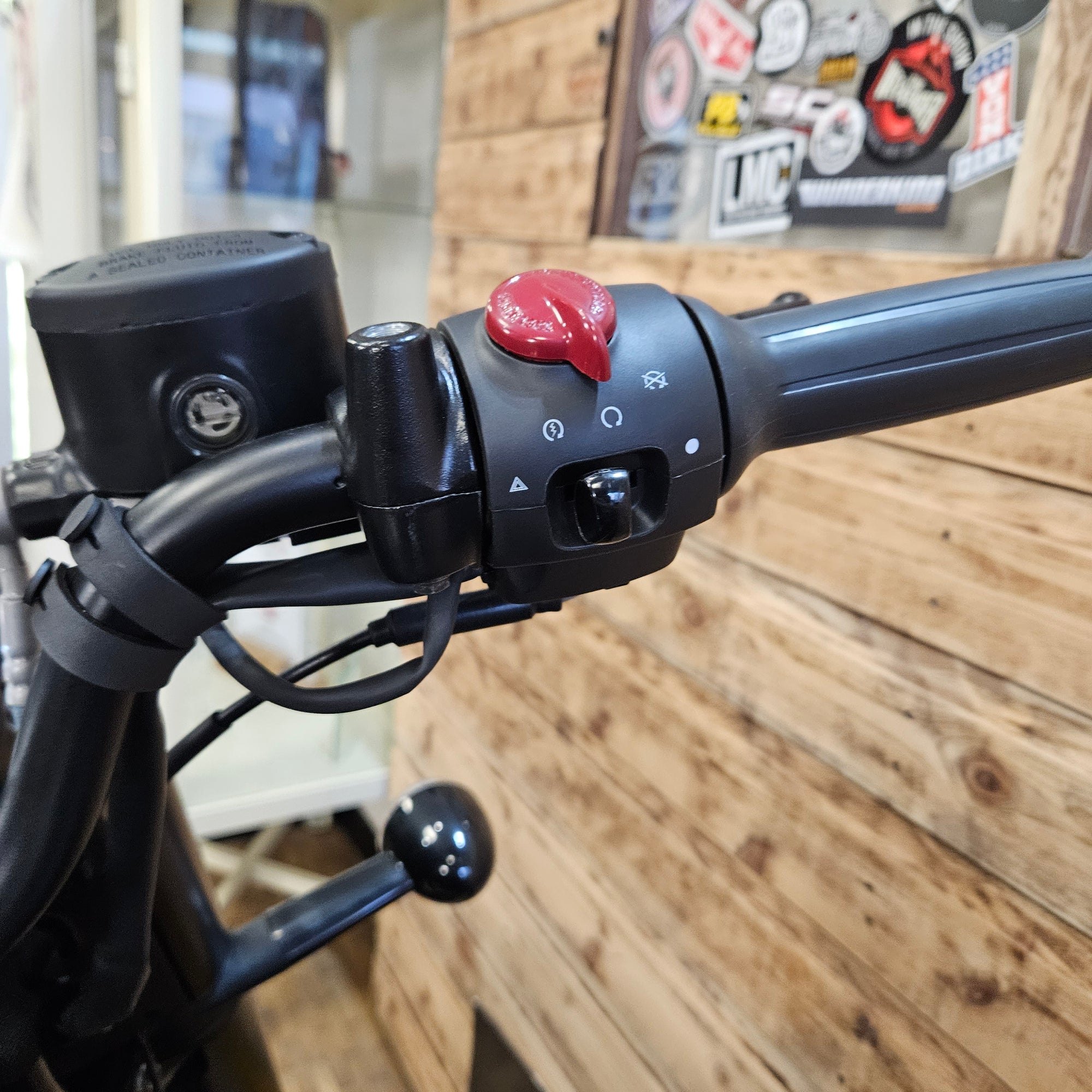 Close-up of a bicycle handlebar with control buttons against a wooden wall background