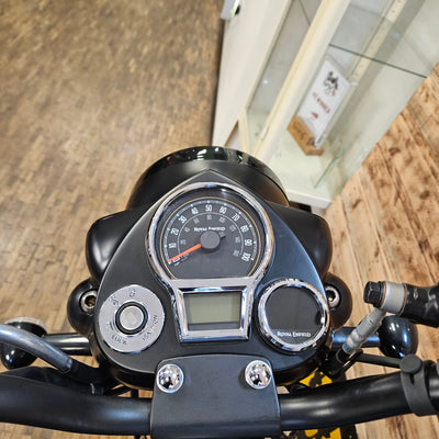 Close-up of a motorcycle dashboard with speedometer and digital display.