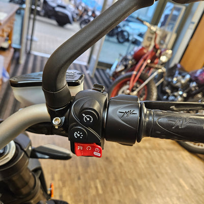 Close-up of a motorcycle handlebar with control buttons in an indoor setting