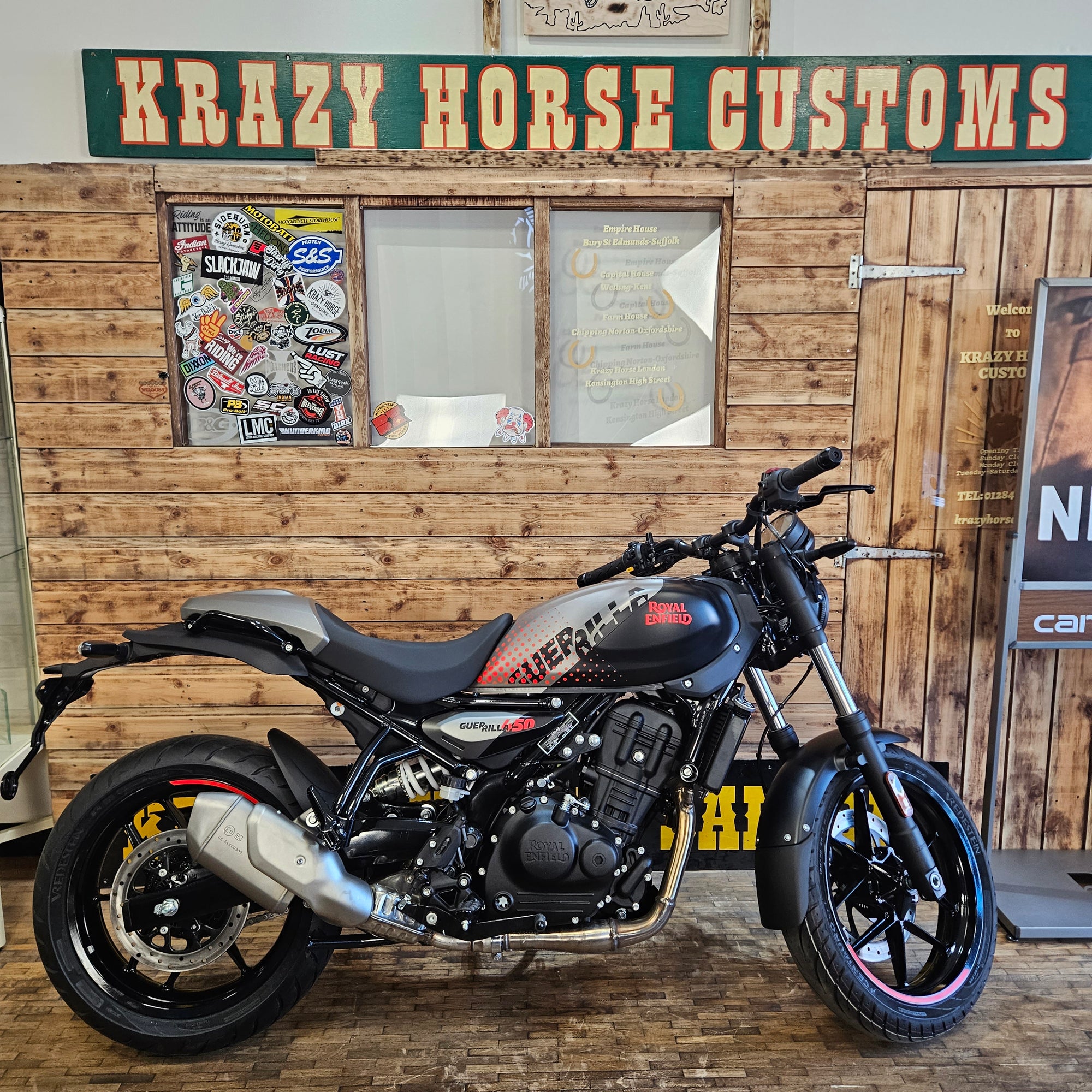 Motorcycle mounted on a wooden wall with 'Krazy Horse Customs' sign.