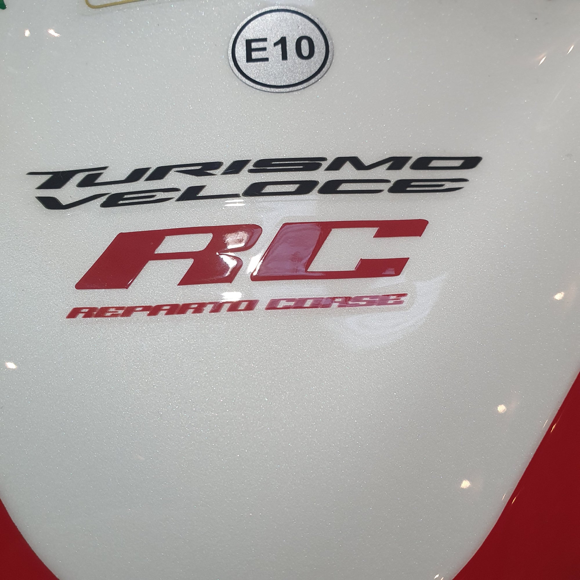 Close-up of a car with 'Turismo Veloce' and 'Ferrari' branding on a white background.