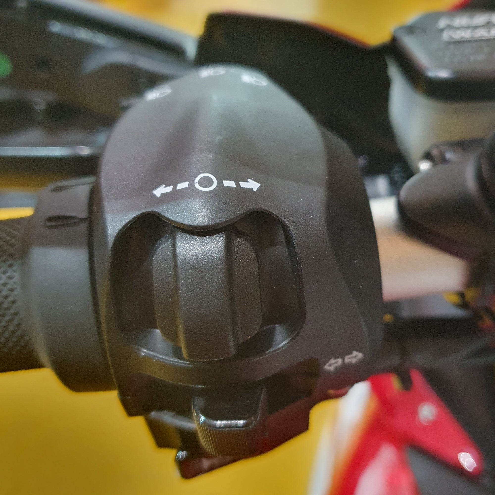 Close-up of a black motorcycle handlebar grip with a blurred colorful background