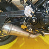 Close-up of a motorcycle exhaust and chain on a yellow surface