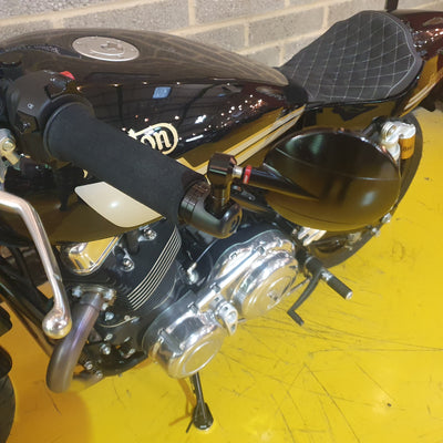 Close-up of a motorcycle with a shiny black seat and chrome details on a yellow floor.