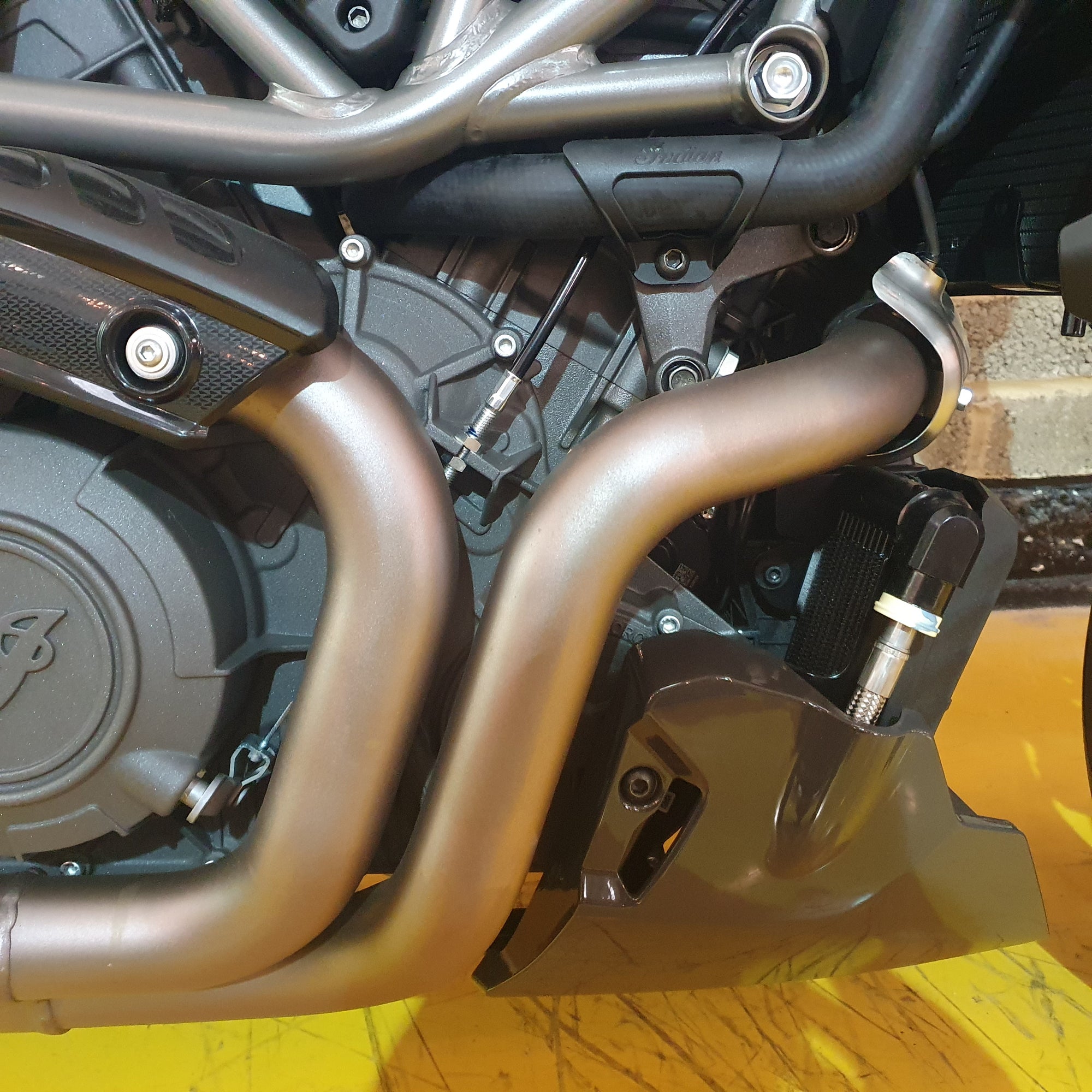 Close-up of a Indian FTR motorcycle exhaust system on a yellow surface