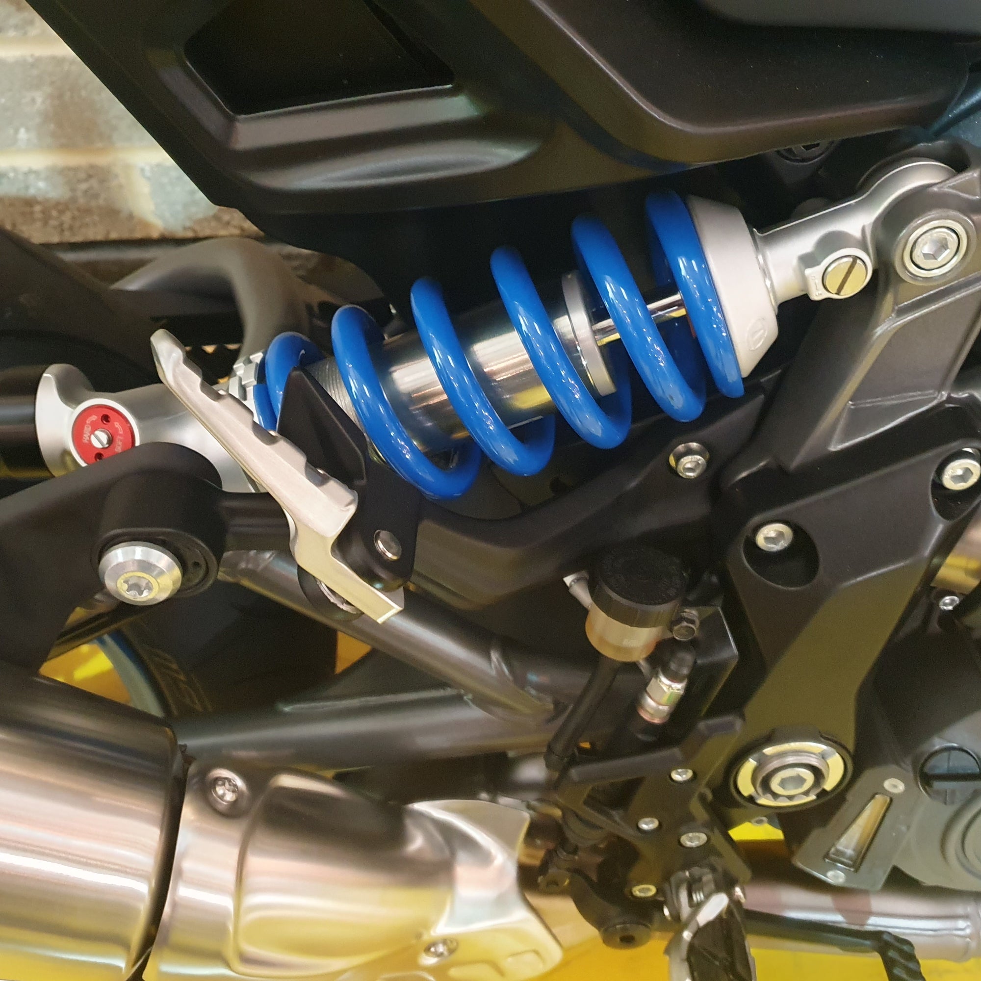 Close-up of a Indian FTR  motorcycle suspension system with blue coil spring