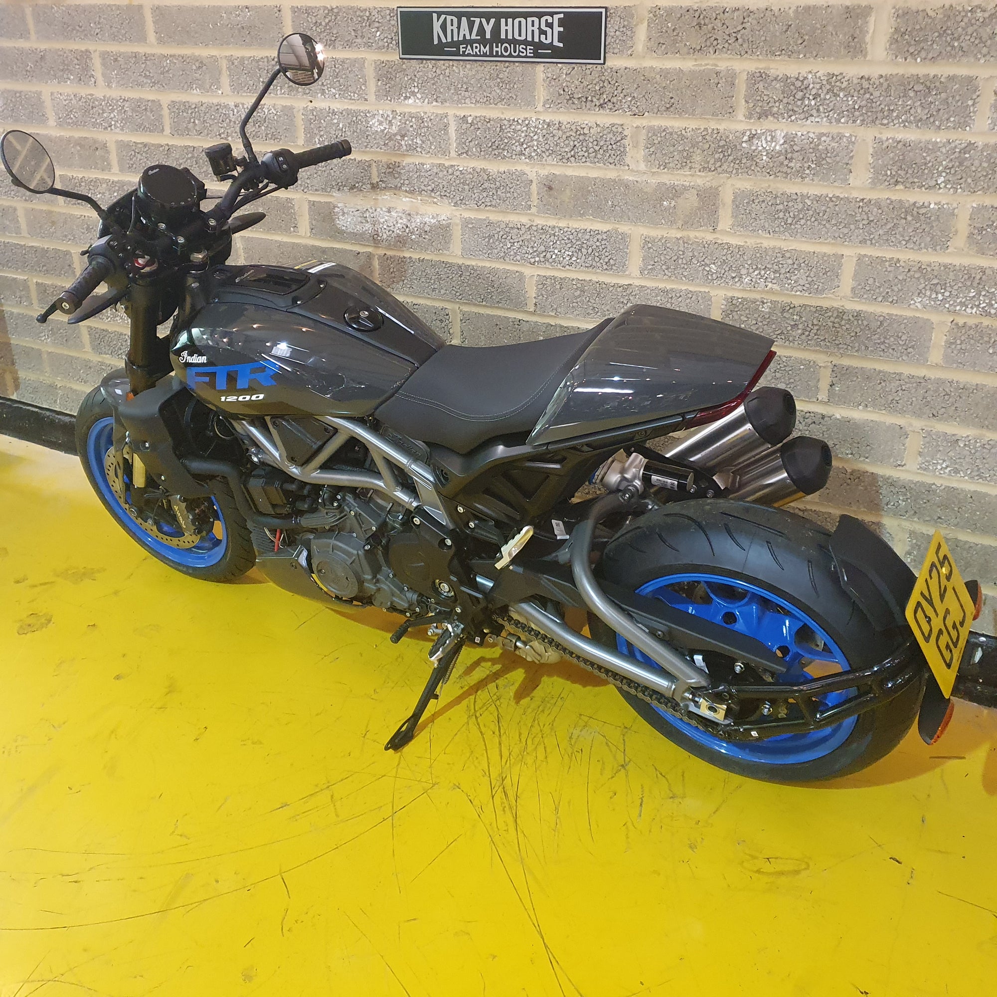 Motorcycle parked against a brick wall on a yellow floor