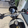 Close-up of a motorcycle's handlebar and front headlight with a blurred background