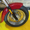 Close-up of a motorcycle wheel with red fender on a yellow surface.