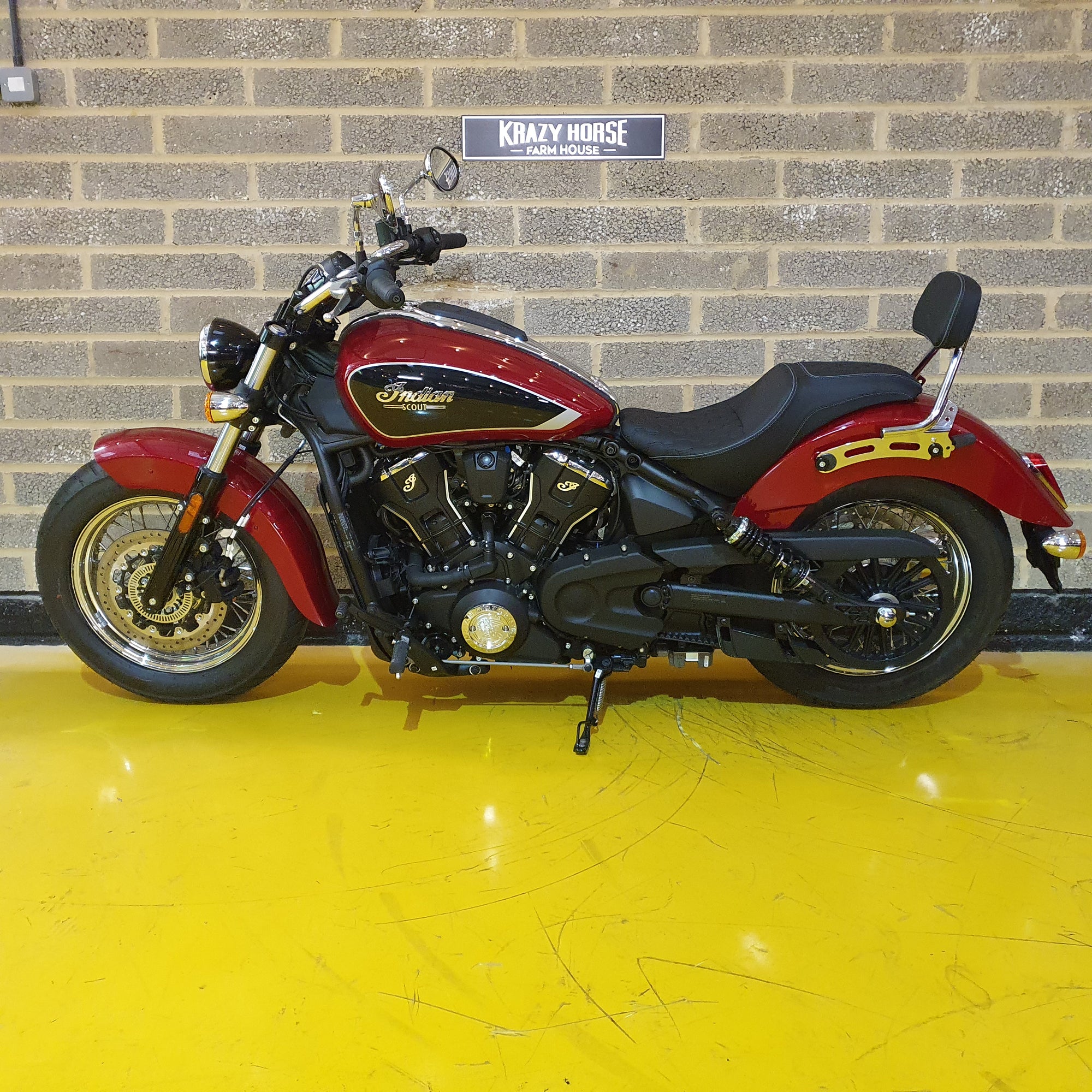 Red Indian motorcycle parked in front of a brick wall.