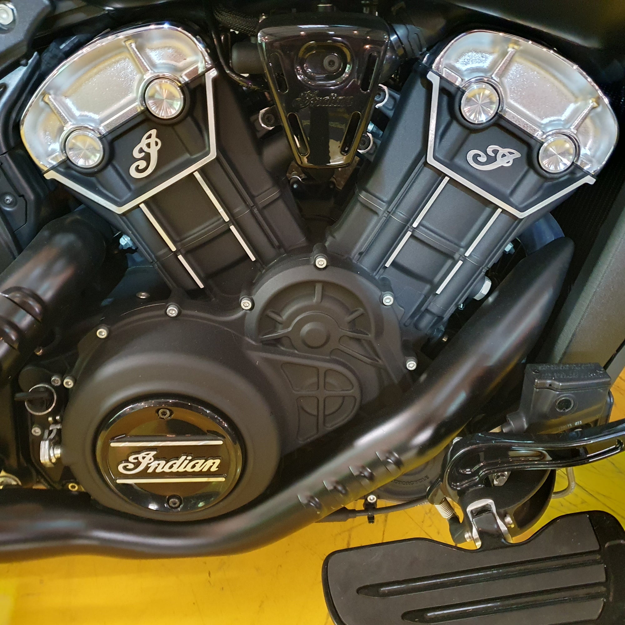 Close-up of a motorcycle engine with 'Indian' branding on a yellow background