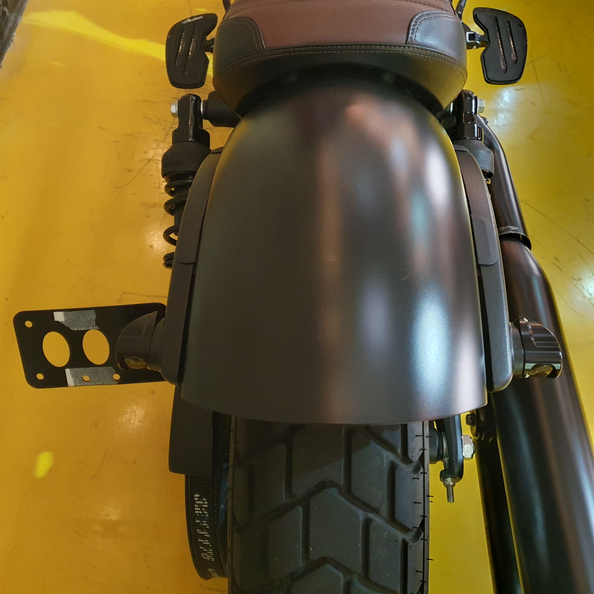 Close-up of a motorcycle fender and tire on a yellow background