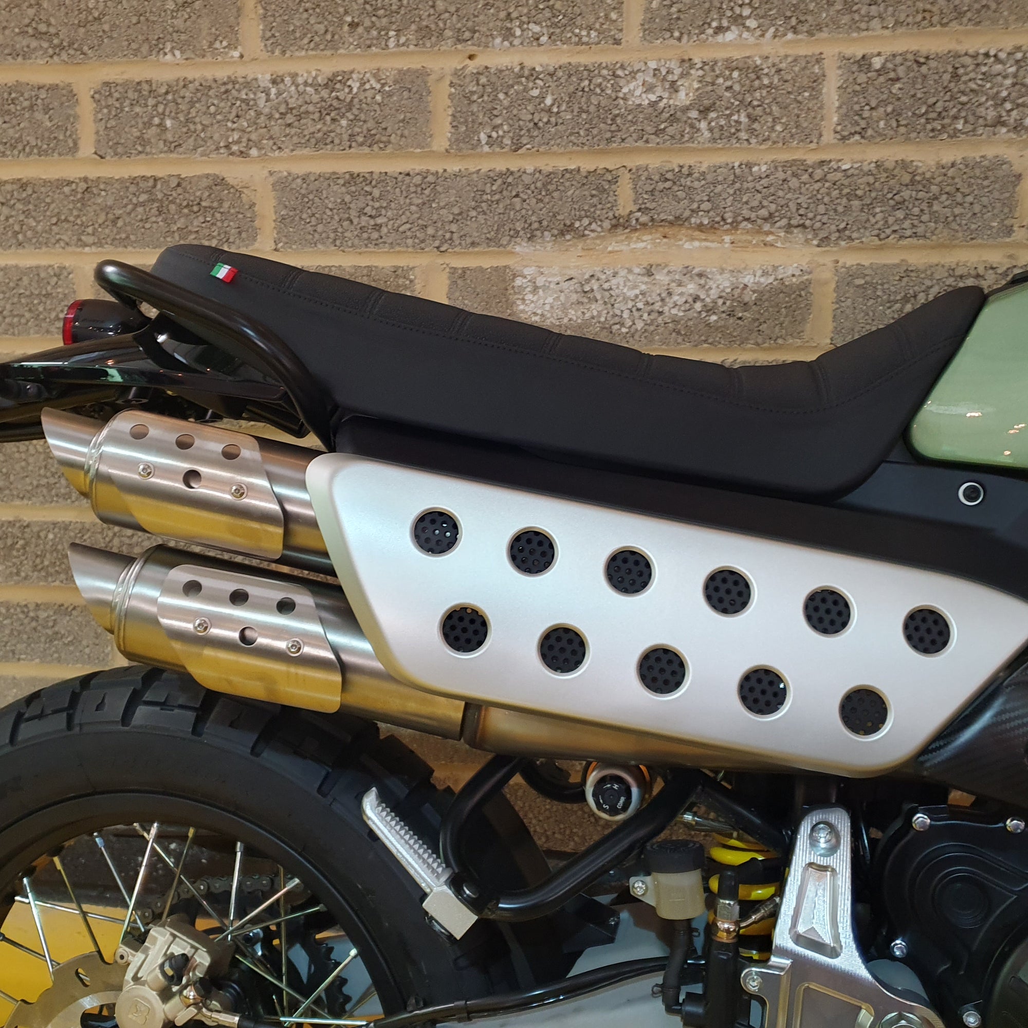 Motorcycle with exhaust pipes against a brick wall